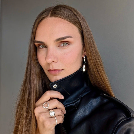 A woman wearing a black leather jacket and a silver-colored ring on her finger.