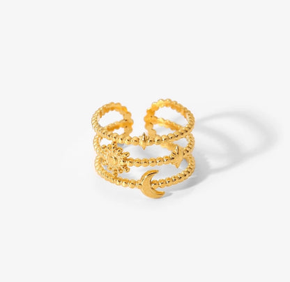 A gold-colored, chunky band ring with a moon and stars design, made from stainless steel with 18k PVD gold plating.