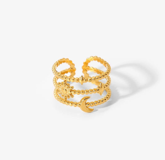 A gold-colored, chunky band ring with a moon and stars design, made from stainless steel with 18k PVD gold plating.